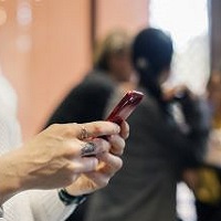 Foto av händer som håller i en mobiltelefon.